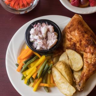 A meal consisting of roasted chicken, mixed vegetables, potatoes, and a side of salad.