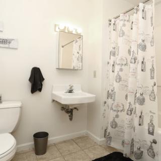 A clean and simple bathroom featuring a sink, toilet, and a decorative shower curtain.