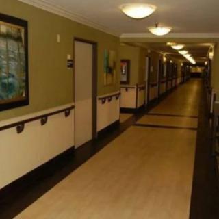 A long, well-lit hallway with paintings on the walls and handrails along the sides.