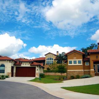 A suburban neighborhood with modern homes under a blue sky with clouds.