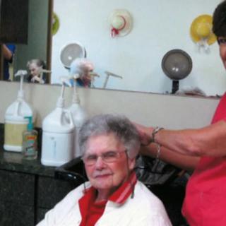 An elderly woman getting her hair done at a salon.