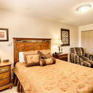 A cozy bedroom featuring a wooden bed frame, matching nightstands, and a comfortable armchair.