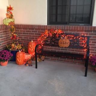 A cozy autumnal setup with pumpkins and fall decorations around a bench.