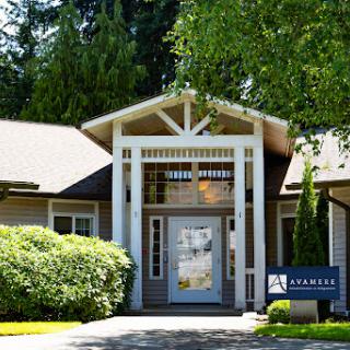 A welcoming entrance to a modern building surrounded by lush greenery.