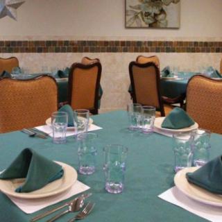 A neatly set dining table in an elegant restaurant with teal napkins and classic chairs.