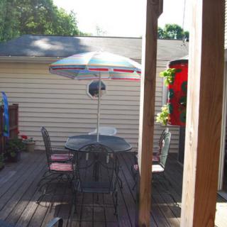 A sunny patio with a table, chairs, and an umbrella on a wooden deck.