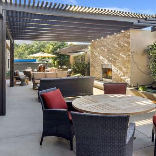 A sunny outdoor patio with comfortable seating, a pergola, and a garden view.