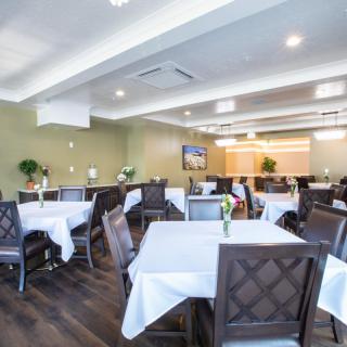 A modern dining room with neatly arranged tables and chairs, featuring elegant table settings.
