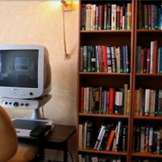 A cozy library corner with a vintage computer and a bookshelf filled with books.
