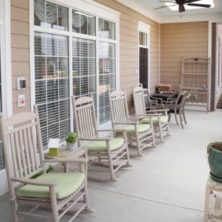 A cozy porch with rocking chairs and small tables, perfect for relaxing outdoors.