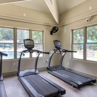A bright gym room with treadmills and large windows offering natural light.
