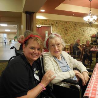 A caregiver and an elderly woman smiling together in a care home setting.