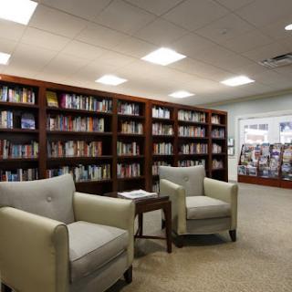 A cozy reading area in a library with comfortable chairs and well-stocked bookshelves.