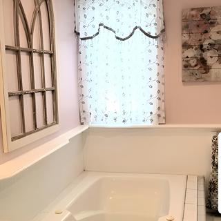 A cozy bathroom with a bathtub, featuring elegant curtains and decorative elements.
