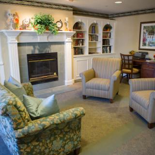 A cozy living room with a fireplace, comfortable seating, and decorative bookshelves.