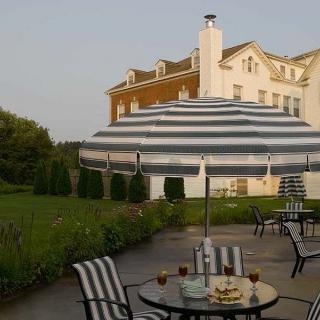 A cozy patio with striped furniture and a large umbrella, next to a grand building.