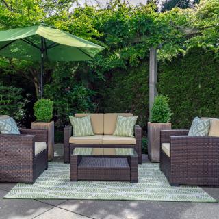 A cozy outdoor patio setup with rattan furniture and lush greenery.