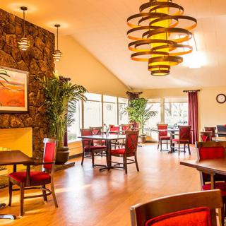 A warmly lit restaurant interior featuring elegant chandeliers and red-cushioned seating.