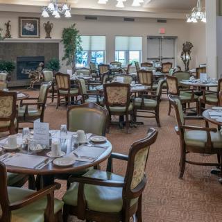 An elegant dining room with multiple tables and chairs, set for guests.