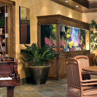 A cozy living room featuring a large aquarium, piano, and stylish furniture.