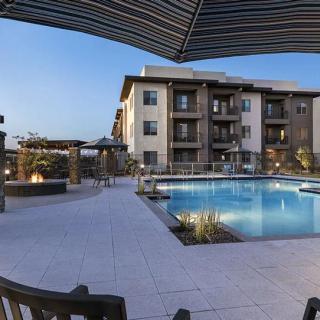 A modern apartment complex with a swimming pool and outdoor seating area in the evening.
