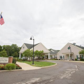 A welcoming entrance to a community facility, featuring a flag and well-maintained landscaping.