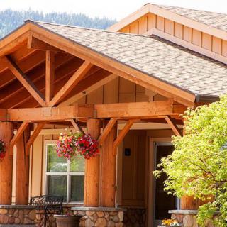 A charming wooden house with a welcoming porch adorned with hanging flowers.