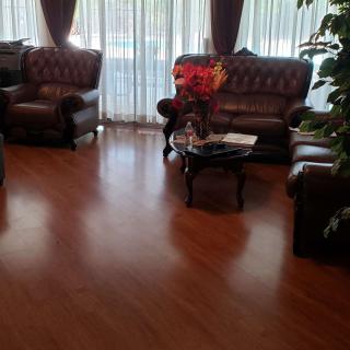 A cozy living room with leather sofas, a coffee table, and curtains filtering light.