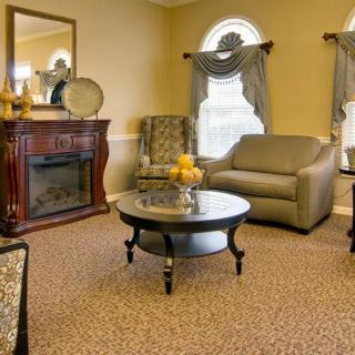 A cozy living room with classic decor featuring a sofa, armchair, and a fireplace.