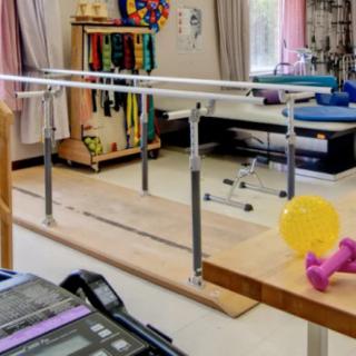 A physical therapy room equipped with parallel bars and various exercise tools.