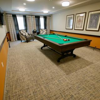 A cozy billiard room featuring a pool table and comfortable seating.