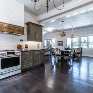 A modern kitchen and dining area featuring dark wood floors and elegant cabinetry.