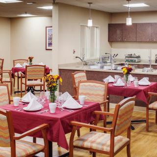 An elegantly arranged dining area with tables set for a meal, complete with floral centerpieces and folded napkins.