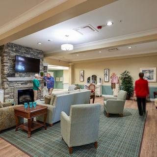 A cozy living room with people socializing around a fireplace and television.
