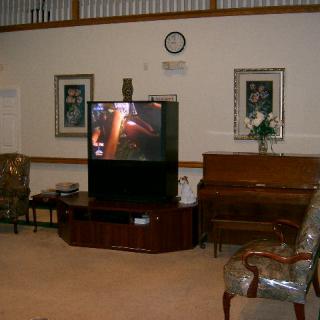 A cozy living room setup with a large television and piano.