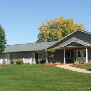 A single-story suburban house with a well-maintained lawn and trees.