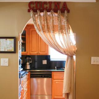 A cozy kitchen view through a decorated archway with curtains.