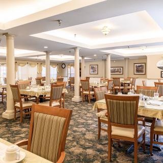 An empty, well-lit dining room with neatly arranged tables and chairs.