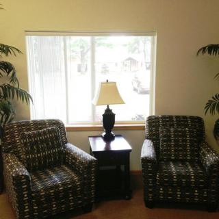 A cozy seating area with two patterned chairs and a lamp in front of a window.
