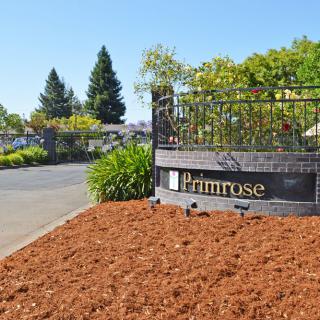 Entrance sign for Primrose Apartments surrounded by well-maintained landscaping.