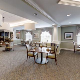 A spacious and elegant dining room with neatly arranged tables and chairs, soft lighting, and large windows.