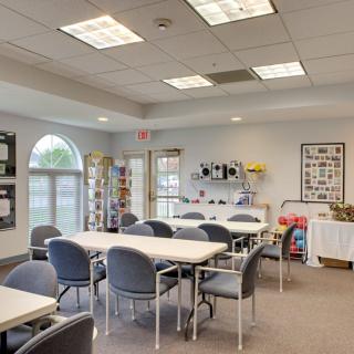 A well-lit classroom or meeting room with tables and chairs arranged for group activities.