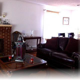 A cozy living room with a dark leather sofa, wooden table, and a brick fireplace.