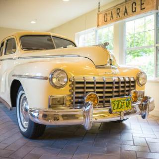 A vintage yellow classic car parked in a well-lit garage.