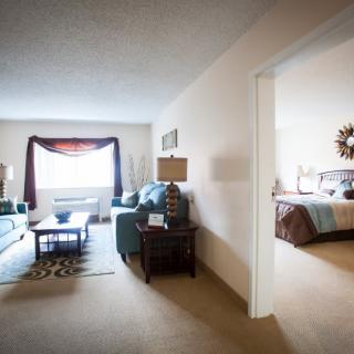 A cozy apartment interior with a living room and an adjacent bedroom.