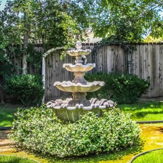 A beautiful multi-tiered fountain surrounded by lush greenery in a garden setting.