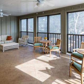 A bright sunroom furnished with comfortable seating and large windows.