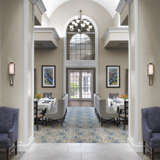 A luxurious dining area with elegant furniture and large arched windows, featuring sophisticated interior design.
