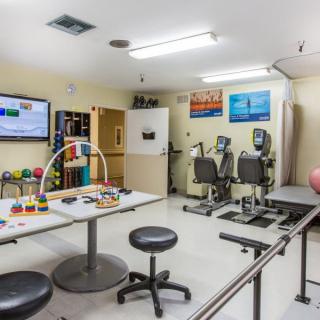 A spacious rehabilitation center equipped with various therapy tools and exercise machines.