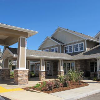 A modern residential building with landscaped surroundings under a clear blue sky.